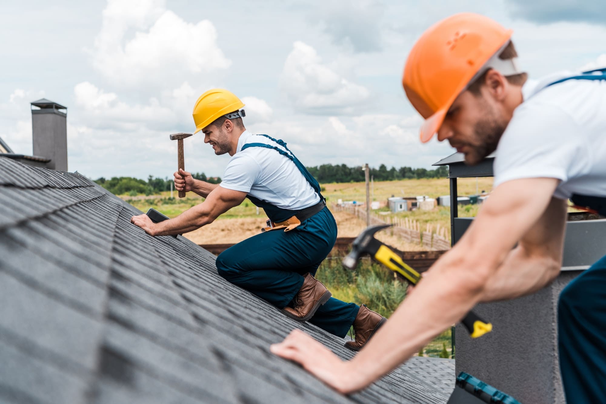selective focus of handsome handyman repairing roof with colleague